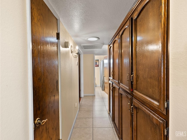 hall featuring a textured ceiling and light tile patterned floors