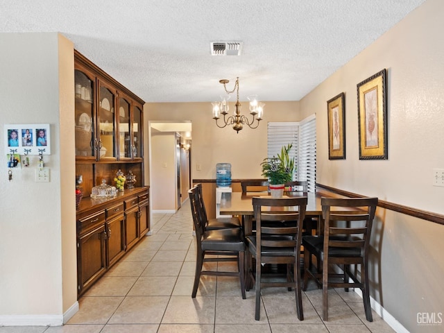 dining area with a textured ceiling, light tile patterned floors, and a notable chandelier