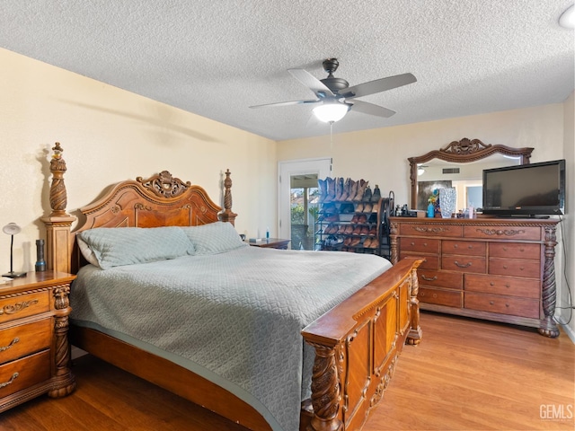 bedroom with a textured ceiling, ceiling fan, and light hardwood / wood-style floors