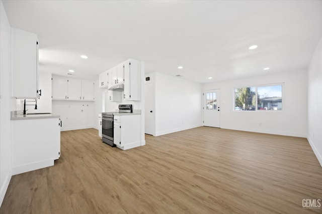 kitchen featuring white cabinets, under cabinet range hood, stainless steel electric range, and open floor plan