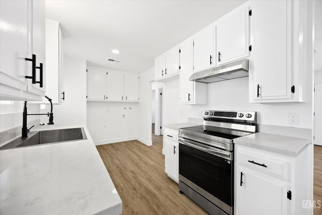 kitchen featuring white cabinets, light countertops, stainless steel electric range oven, and under cabinet range hood