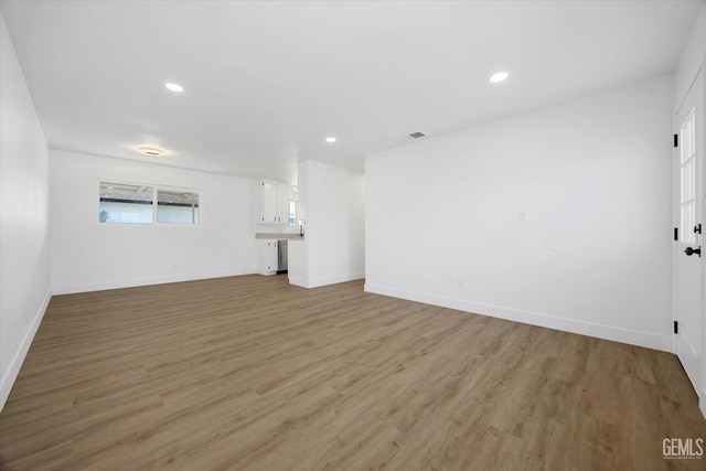 unfurnished living room with recessed lighting, baseboards, and light wood finished floors