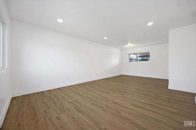 empty room with dark wood-style floors, recessed lighting, and baseboards