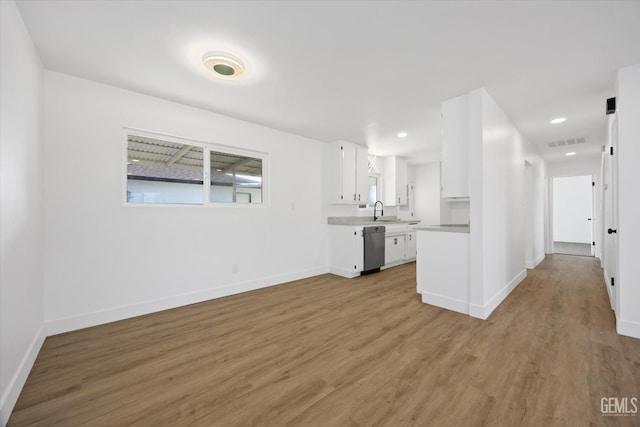 kitchen with light countertops, visible vents, stainless steel dishwasher, light wood-style floors, and white cabinetry