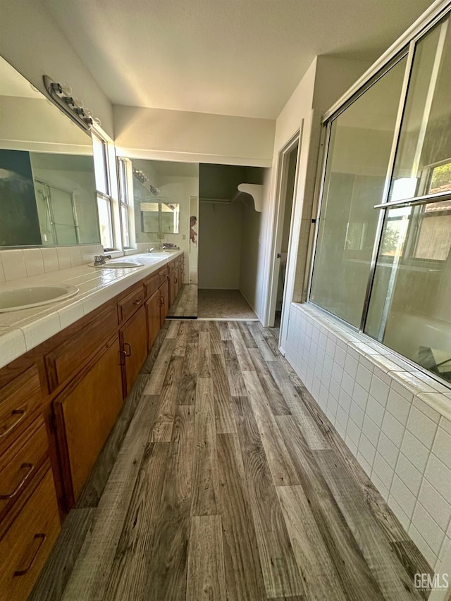5821 Willowcrest St, Bakersfield, CA 93313 - bathroom with wood finished floors, double vanity, an enclosed shower, and tiled bath