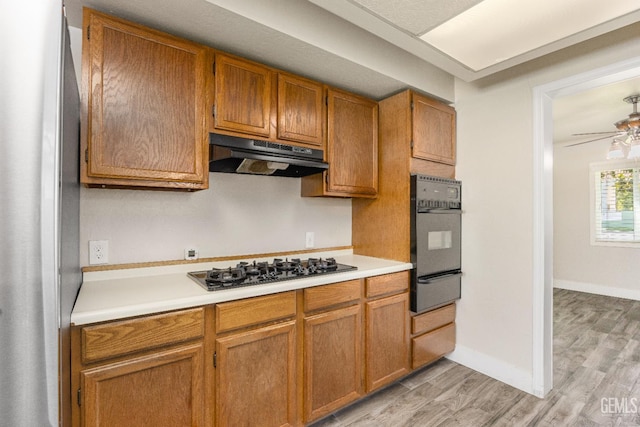 1701 Elm St, Bakersfield, CA 93301 - kitchen featuring under cabinet range hood, black appliances, a warming drawer, light countertops, and light wood-style flooring
