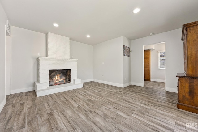 1701 Elm St, Bakersfield, CA 93301 - unfurnished living room with light wood-type flooring, a brick fireplace, baseboards, and recessed lighting