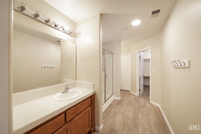 bathroom featuring hardwood / wood-style flooring, vanity, and a shower with shower door