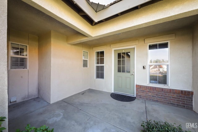 view of exterior entry with a patio area