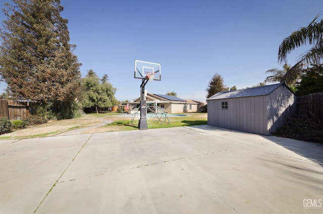 view of patio / terrace with a storage shed and basketball hoop