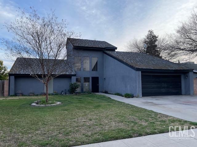 view of front of property with an attached garage, driveway, a front lawn, and stucco siding