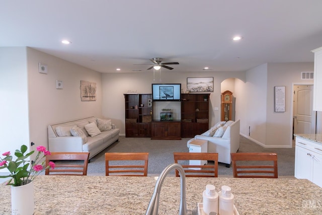 living area featuring arched walkways, recessed lighting, carpet floors, visible vents, and baseboards