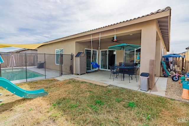 back of property featuring a fenced in pool, a patio, stucco siding, ceiling fan, and fence