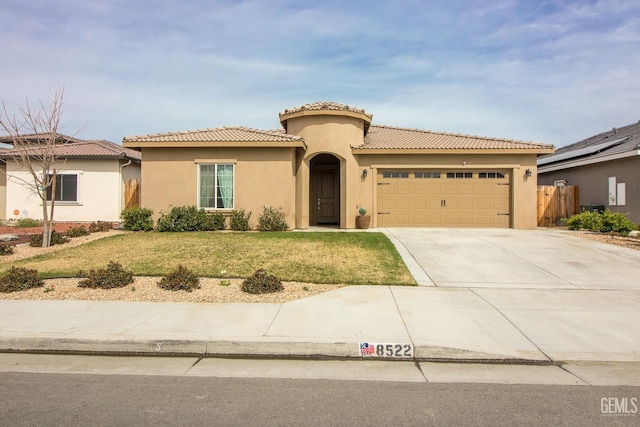 mediterranean / spanish-style home with a garage, fence, driveway, stucco siding, and a front yard