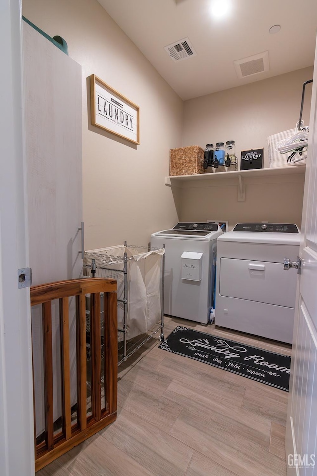 laundry room featuring laundry area, light wood finished floors, independent washer and dryer, and visible vents