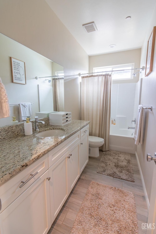 bathroom featuring visible vents, toilet, shower / tub combo, vanity, and baseboards