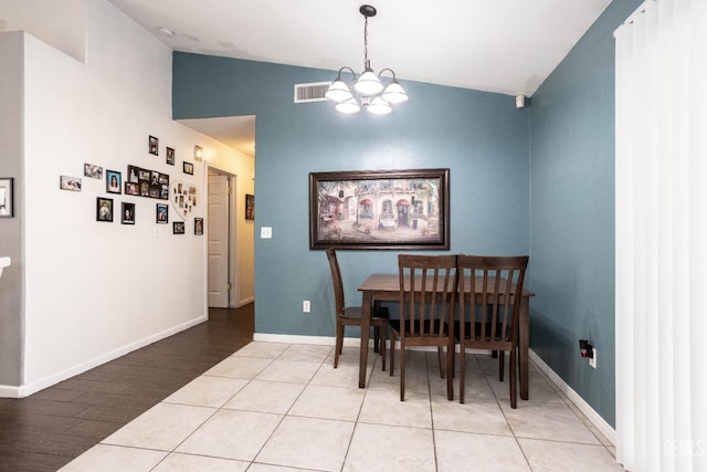 tiled dining area featuring a chandelier and vaulted ceiling