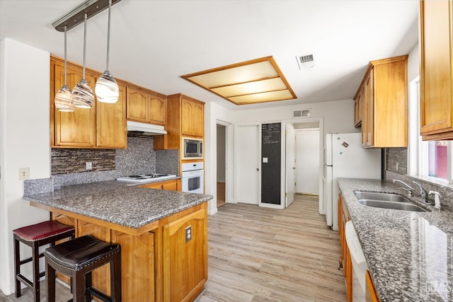 5702 San Pierre Ct, Bakersfield, CA 93308 - kitchen featuring white appliances, light wood-style floors, backsplash, and under cabinet range hood