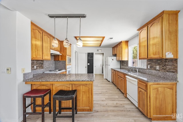 5702 San Pierre Ct, Bakersfield, CA 93308 - kitchen featuring white appliances, under cabinet range hood, a peninsula, light wood finished floors, and decorative backsplash