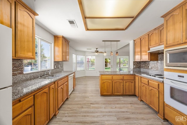 5702 San Pierre Ct, Bakersfield, CA 93308 - kitchen featuring white appliances, light wood-style flooring, backsplash, and a peninsula