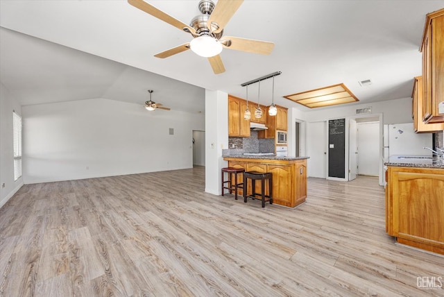 5702 San Pierre Ct, Bakersfield, CA 93308 - kitchen featuring a ceiling fan, a peninsula, tasteful backsplash, light wood finished floors, and a kitchen breakfast bar