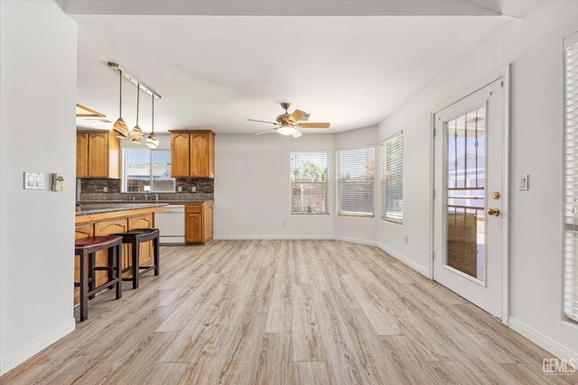 5702 San Pierre Ct, Bakersfield, CA 93308 - kitchen with light wood-style floors, tasteful backsplash, brown cabinetry, a ceiling fan, and hanging light fixtures