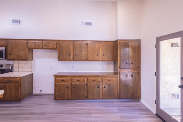 3705 Wilcox Way, Bakersfield, CA 93309 - kitchen featuring stainless steel appliances, light wood-style flooring, tile counters, and decorative backsplash