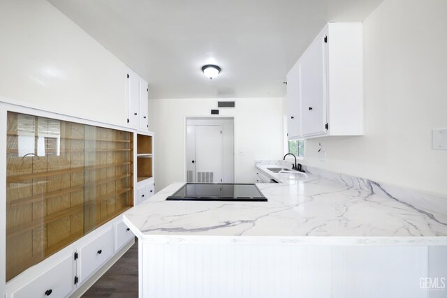 1312 Shattuck Ave, Bakersfield, CA 93305 - kitchen with black electric stovetop, white cabinets, light stone counters, and a peninsula