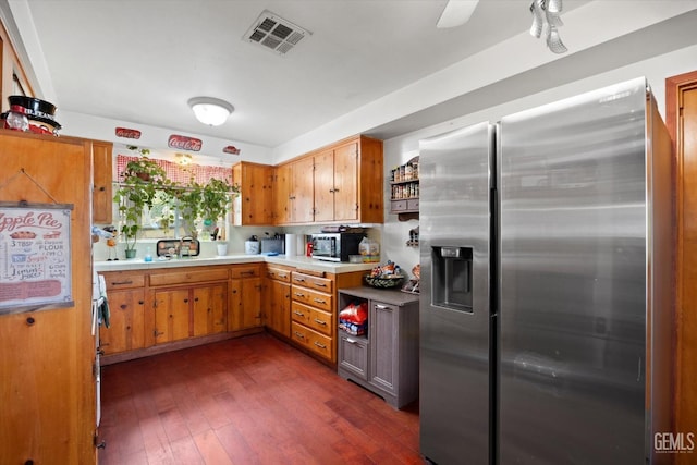 kitchen with stainless steel fridge with ice dispenser, brown cabinets, dark wood-style flooring, and visible vents