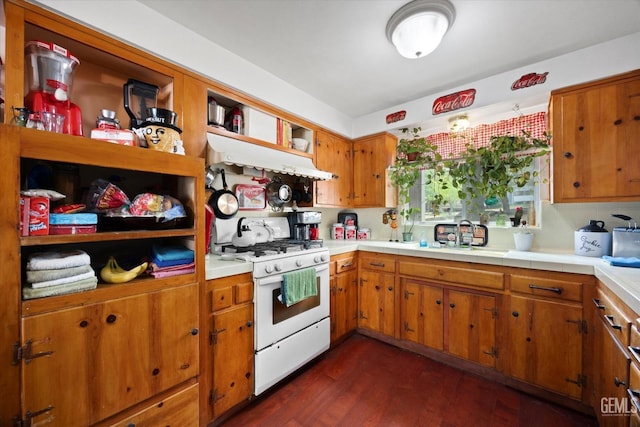kitchen featuring brown cabinets, a sink, light countertops, white range with gas stovetop, and dark wood-style floors