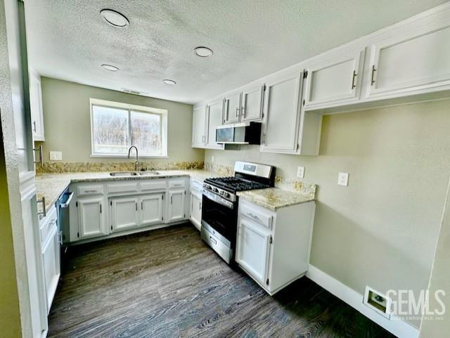 2004 Magdelena Ave, Bakersfield, CA 93307 - kitchen featuring stainless steel range with gas cooktop, a sink, dark wood-type flooring, white cabinetry, and extractor fan