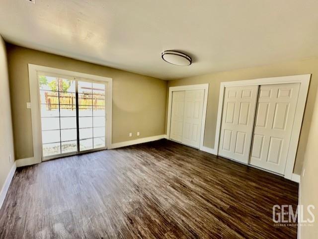 2004 Magdelena Ave, Bakersfield, CA 93307 - unfurnished bedroom featuring two closets, dark wood finished floors, and baseboards