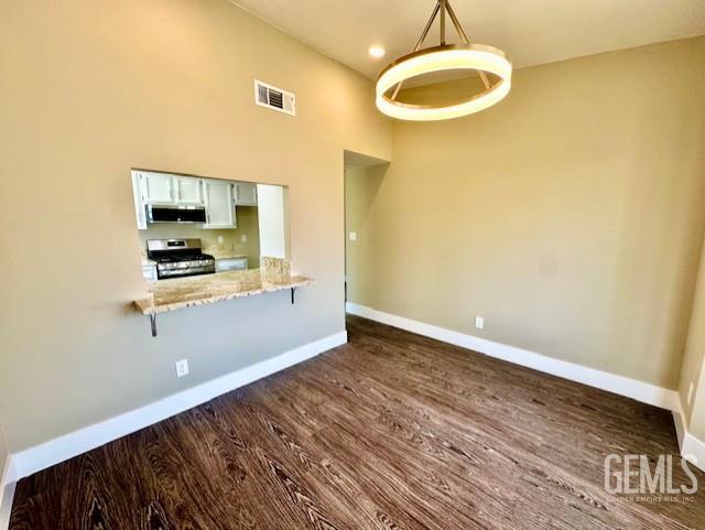 2004 Magdelena Ave, Bakersfield, CA 93307 - kitchen featuring appliances with stainless steel finishes, baseboards, a kitchen breakfast bar, dark wood-style floors, and hanging light fixtures