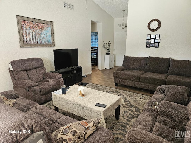 living room with an inviting chandelier, wood-type flooring, a textured ceiling, and vaulted ceiling