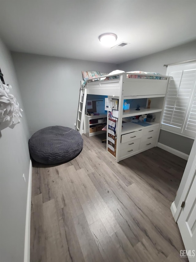 bedroom featuring baseboards, visible vents, and light wood finished floors