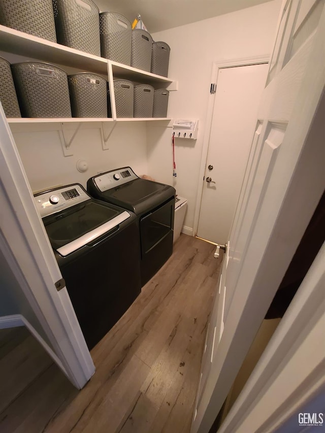 laundry room with laundry area, baseboards, separate washer and dryer, and wood finished floors