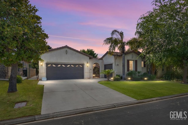 4702 Aviara Dr, Bakersfield, CA 93312 - mediterranean / spanish home featuring a garage, driveway, stucco siding, a lawn, and a gate