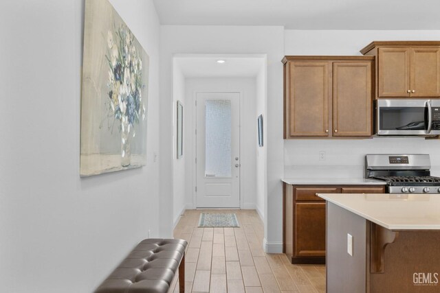 3308 Whispering Brook Ln, Shafter, CA 93263 - kitchen with light wood-style floors, light countertops, brown cabinetry, stainless steel appliances, and baseboards