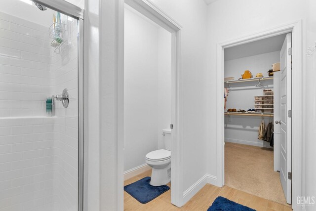 3308 Whispering Brook Ln, Shafter, CA 93263 - full bathroom featuring wood finished floors, toilet, baseboards, a walk in closet, and a shower stall