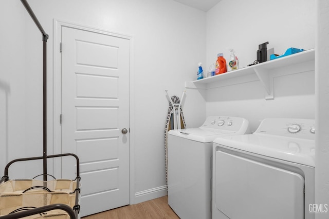 washroom with baseboards, laundry area, washing machine and dryer, and light wood-type flooring