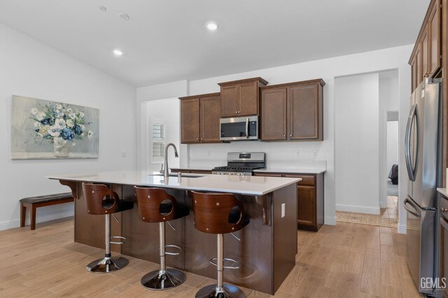 3308 Whispering Brook Ln, Shafter, CA 93263 - kitchen with a kitchen breakfast bar, appliances with stainless steel finishes, a center island with sink, a sink, and light wood-style flooring