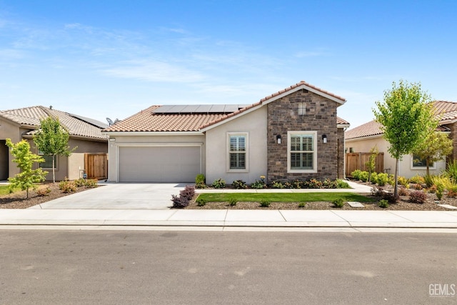 mediterranean / spanish home with a tiled roof, driveway, a garage, roof mounted solar panels, and stucco siding