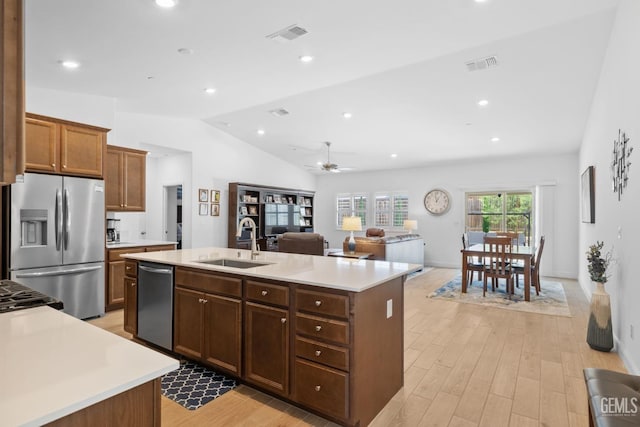 kitchen with a sink, light countertops, an island with sink, stainless steel appliances, and visible vents