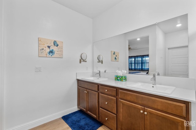 full bath featuring a sink, a ceiling fan, double vanity, and wood finished floors