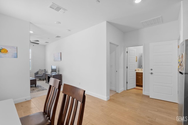 hallway with baseboards, visible vents, and light wood-type flooring