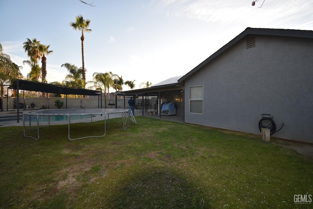 view of yard with a trampoline, a fenced backyard, and a fenced in pool