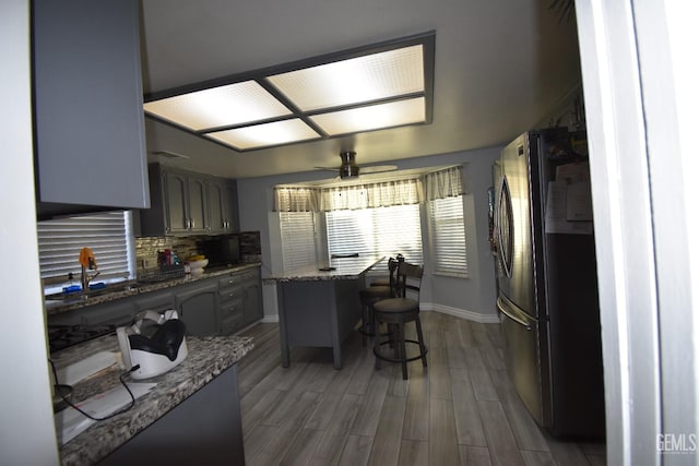 kitchen featuring a center island, tasteful backsplash, a ceiling fan, freestanding refrigerator, and wood finished floors