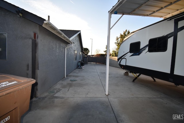 exterior space with a carport, a patio, fence, and stucco siding