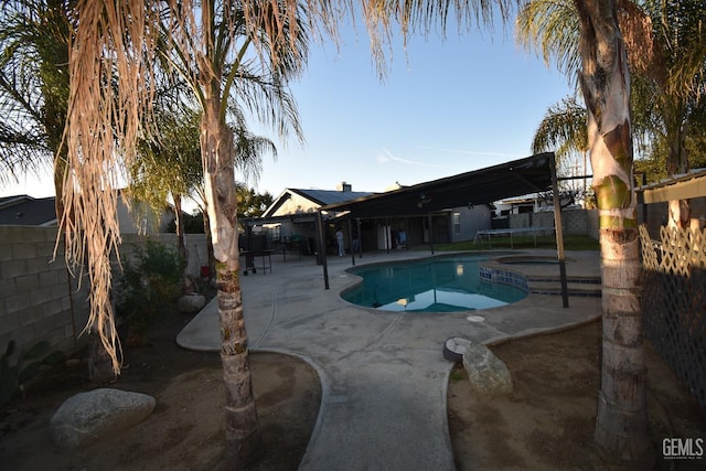 view of swimming pool with a trampoline, a patio area, a fenced backyard, and a fenced in pool