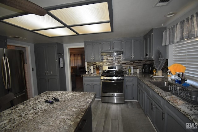 kitchen featuring visible vents, gray cabinetry, appliances with stainless steel finishes, light stone countertops, and under cabinet range hood